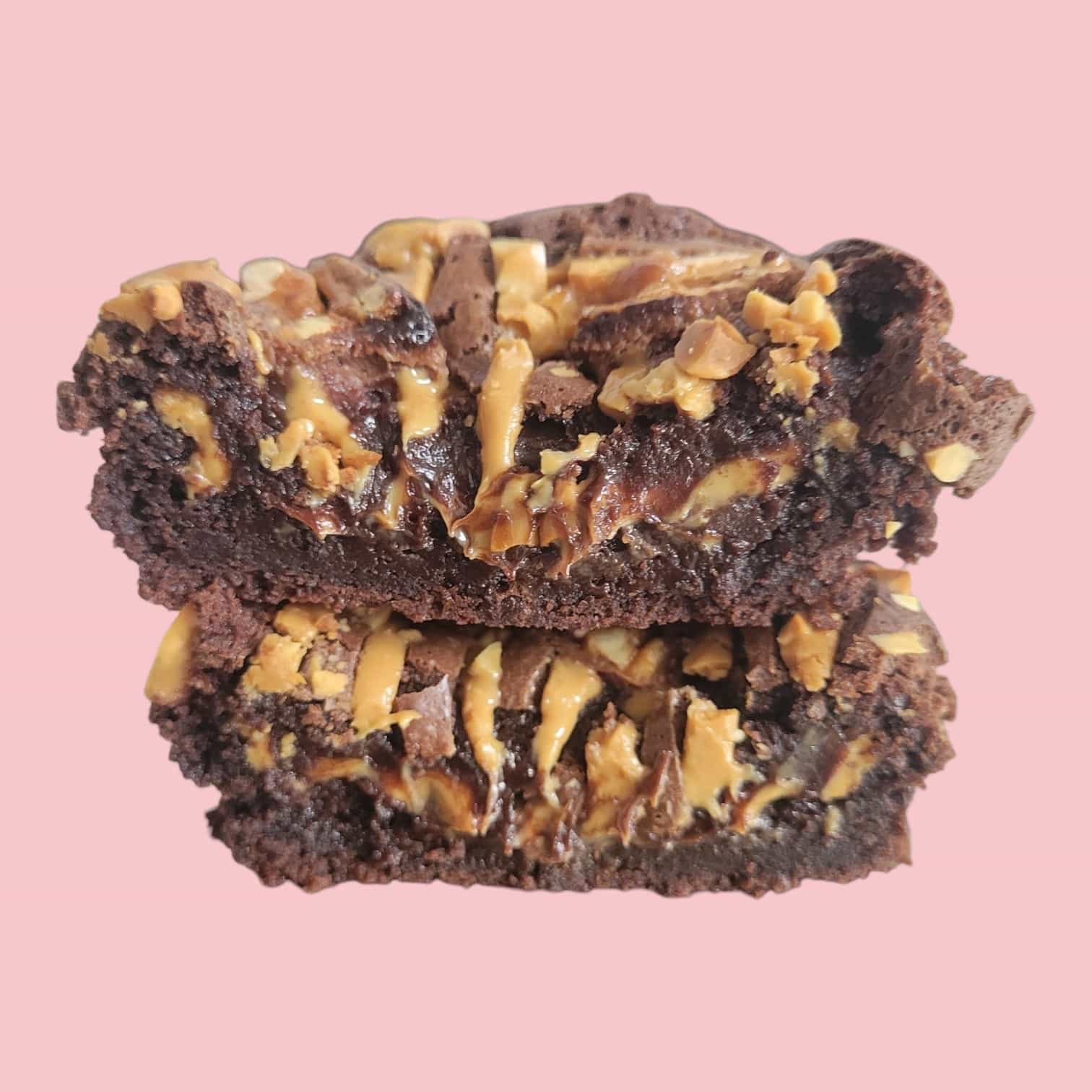brownie snickers beurre de cacahuètes coupé en deux et empilé l'un sur l'autre.