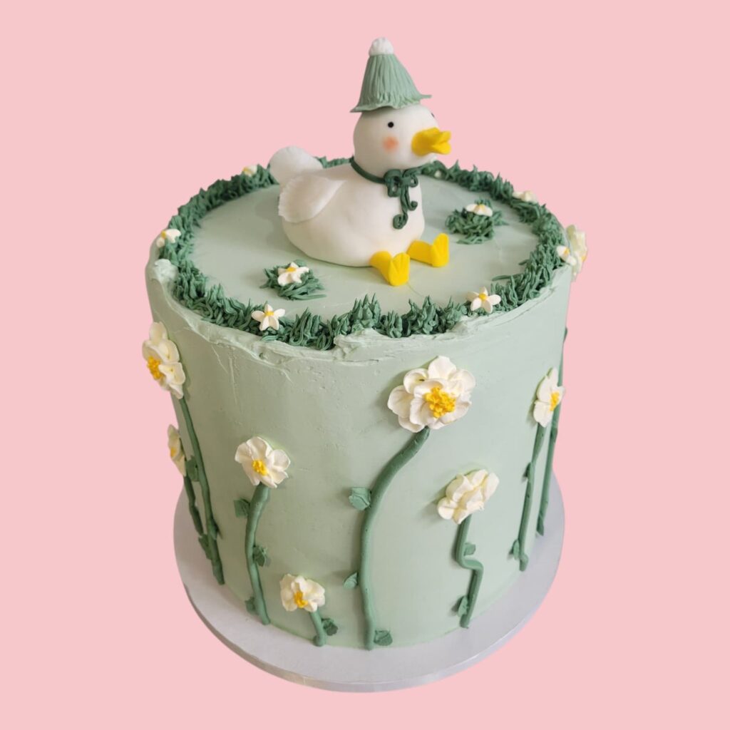 Layercake couleur vert avec un canard modelé au sommet et des Marguerites tout autour